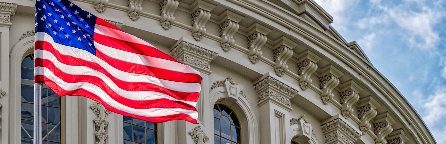 The American flag waves in front of the US Capitol Building