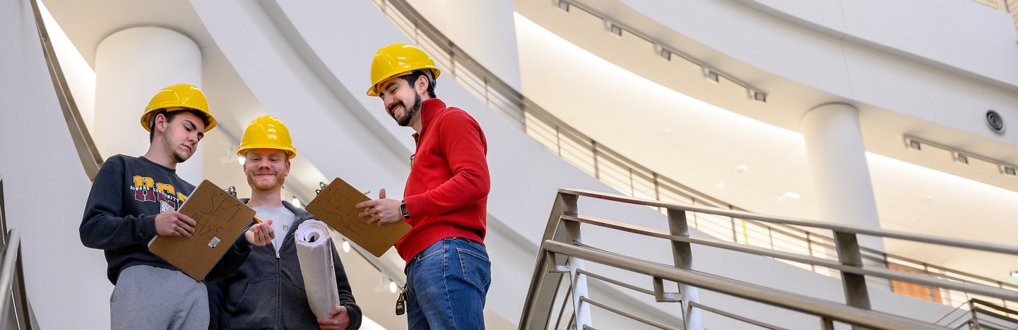 Three students with hard hats standing in community college