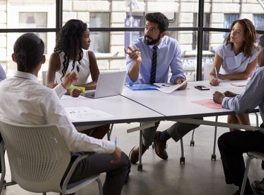 Business professionals gather around a table 