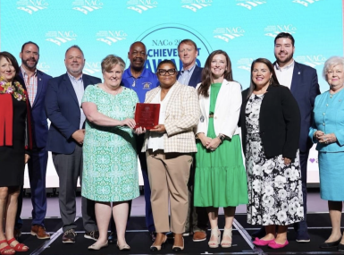 Then-NACo President Mary Jo McGuire of Ramsey County, Minn. (far left) pauses for a photo with Guilford County, N.C. staff after announcing their win July 14 in the Best in Category NACo Achievement Award in the Human Services category, at the NACo Annual Conference in Hillsborough County, Fla. Photo by Denny Henry