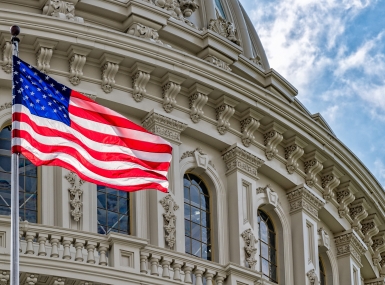 The American flag waves in front of the US Capitol Building