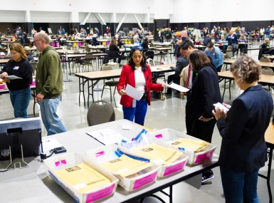 Paulina Gutiérrez, executive director of the Milwaukee Election Commission, middle, works on securing the tabulation machines after learning that the doors of the machines at the central counting facility at the Baird Center were not properly sealed on Election Day, Nov. 5, 2024. Joe Timmerman / Wisconsin Watch