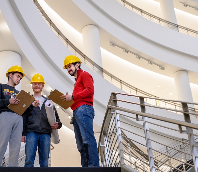 Three students with hard hats standing in community college