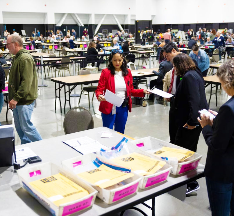 Paulina Gutiérrez, executive director of the Milwaukee Election Commission, middle, works on securing the tabulation machines after learning that the doors of the machines at the central counting facility at the Baird Center were not properly sealed on Election Day, Nov. 5, 2024. Joe Timmerman / Wisconsin Watch