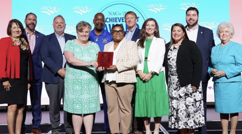 Then-NACo President Mary Jo McGuire of Ramsey County, Minn. (far left) pauses for a photo with Guilford County, N.C. staff after announcing their win July 14 in the Best in Category NACo Achievement Award in the Human Services category, at the NACo Annual Conference in Hillsborough County, Fla. Photo by Denny Henry