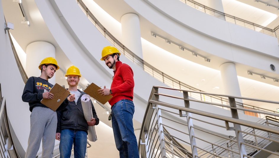 Three students with hard hats standing in community college